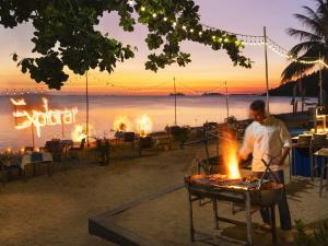 a man cooking food on a grill on the beach at Explorar Koh Phangan - Adults Only Resort and Spa in Haad Rin