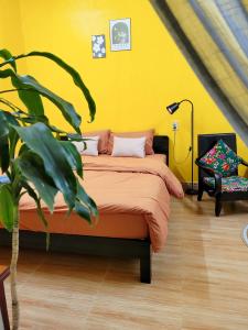 Tiny House Cat Ba في كات با: غرفة نوم صفراء فيها سرير وزرع