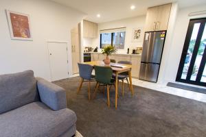 a living room with a couch and a table with chairs at Tranquil 2 bed townhouse w/carparking in Christchurch