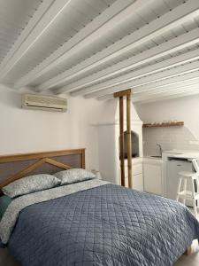 una camera con letto blu e una cucina di Anais a Mykonos Città