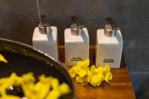 grupa trzech butelek mydła na stole z żółtymi kwiatami w obiekcie Vayang Retreat and Camping w mieście Hòa Bình