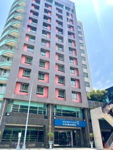 a tall building with red windows in front of it at Golden Tulip Zhong Xin Hotel Taichung in Taichung