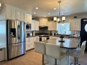 Una cocina con una mesa y un refrigerador de acero inoxidable. en HC Accessible 4 Bed 3 Bath with Sparkling Pool and Spa-we have lifts and roll in shower, en Santee