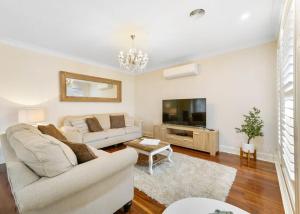 a living room with a couch and a tv at Roselawn Manor - 5 Bedroom Entertainer in Orange