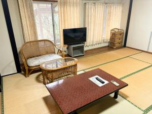 a living room with a couch a table and a tv at エコホテル　湯の児荘 in Minamata +13 photos