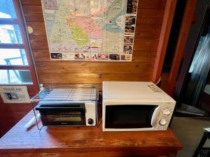 a microwave and a toaster oven sitting on a table at Little Alaskan Guest House in Hakuba