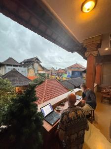 a couple of men sitting at a table with a laptop at Nua House in Ubud