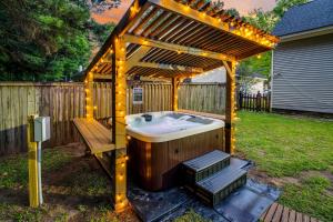 a hot tub under a wooden pergola with a bench at Lowcountry haven - game rm + king bds, mins 2 dwtn in Charleston
