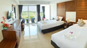 a hotel room with two beds and a television at David Residence in Nai Yang Beach