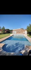 a swimming pool with blue water in a yard at Casa Rodante en granja in Santiago del Estero