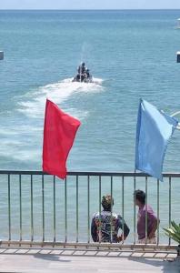 dos personas sentadas en una valla viendo un elefante en el agua en Clarin's Beach, en Pagbilao