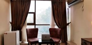 um quarto com uma janela com 2 cadeiras e um computador portátil numa mesa em Islamabad Premium Hotel em Islamabad