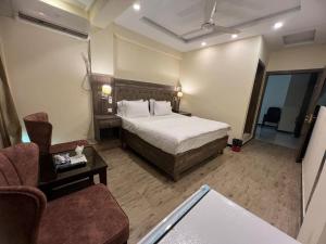 um quarto de hotel com uma cama e uma cadeira em Islamabad Premium Hotel em Islamabad