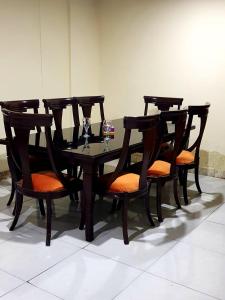 Islamabad Premium Hotel في اسلام اباد: طاولة وكراسي خشبية مع وسائد برتقالية