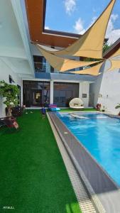 uma casa com piscina com relva verde em Clarin's Beach em Pagbilao