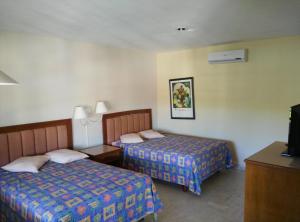 a hotel room with two beds and a television at Hotel Debliz Xpujil in Chicanna