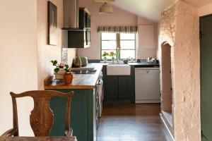 a kitchen with green cabinets and a wooden chair at Stour Valley Cottage in Wimborne Minster