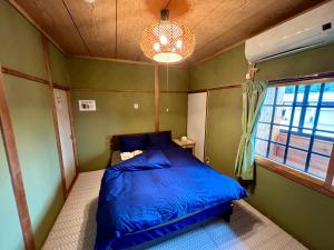 a bedroom with a blue bed and a window at Little Alaskan Guest House in Hakuba