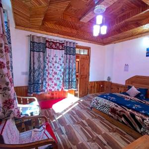 a bedroom with a bed and a chair in a room at Alpine Homestay at Gadagusain in Banjār