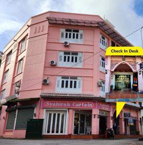 ein rosafarbenes Gebäude mit einem Schild, das das Check-in-Deck liest in der Unterkunft Uptown Eco Hotel in Kuala Terengganu