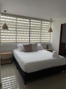 een slaapkamer met een groot wit bed en ramen met luiken bij LILI in Cartagena