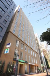 um edifício alto com um sinal em frente em Keio Presso Inn Ikebukuro em Tóquio