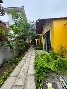 a stone walkway next to a yellow building at Azalea Tam Coc Ninh Bình in Ninh Binh