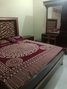 a bed with a red comforter on top of it at Gujrat Guest House in Gujrāt