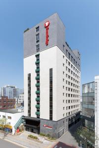 a tall white building with a red sign on it at Travelodge Myeongdong Namsan in Seoul