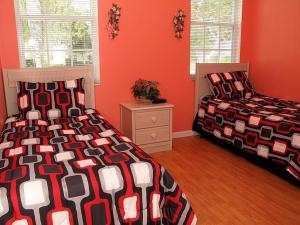 twee bedden in een kamer met rode muren bij Fan Palm Villa 8208 in Kissimmee