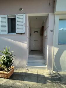 a white building with a white door and a plant at Elena s apartment in Megara