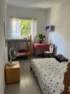 a bedroom with a bed and a desk and a window at Xixova Hostel Japui são Vicente in Praia Grande