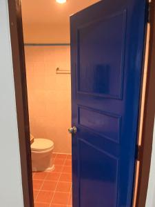 a bathroom with a toilet and a blue door at โรงแรมเมโทร2 Metro2 in Satun