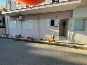 a white building with white shuttered windows and a street at Elena s apartment in Megara