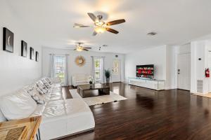 een woonkamer met een witte bank en een plafondventilator bij Gorgeous open concept 4 BR with heated pool and lounge area in Fort Lauderdale