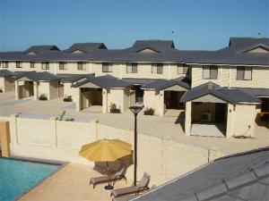 a building with a pool and a yellow umbrella at Port Denison Beach Resort in Port Denison