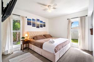 a bedroom with a bed and two windows at Gorgeous open concept 4 BR with heated pool and lounge area in Fort Lauderdale