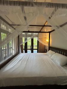 1 dormitorio con cama blanca y mosquitera en White Villa Goyambokka en Tangalle