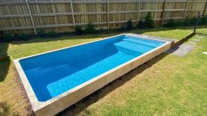 a large blue swimming pool in a yard at Surf and Dunes in Yamba