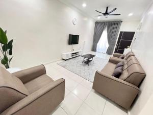 uma sala de estar com dois sofás e uma televisão em SAFRA HOMESTAY PERLIS em Arau