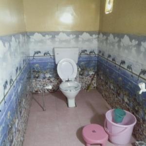 a bathroom with a toilet with blue and white tiles at GREEN VALLEY CAMPING & ADVENTURE in Nainital