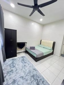 - une chambre avec un lit et un ventilateur de plafond dans l'établissement SAFRA HOMESTAY PERLIS, à Arau