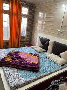 Una cama con una manta de colores encima. en Dream Land Hotel, en Jammu