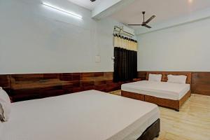 a bedroom with two beds and a ceiling fan at Nidhivan Guest House in Kishangarh