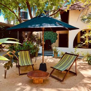 ein Tisch und zwei Stühle unter einem großen Schirm in der Unterkunft Little Lagoon Hostel in Arugam Bay