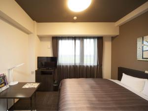 um quarto de hotel com uma cama e uma televisão em Hotel Route Inn Ono em Ono