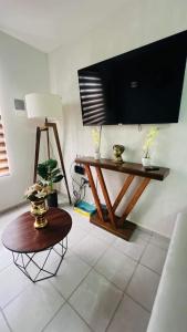 a living room with a table and a tv on the wall at Departamento Ajal Tulum in Tulum