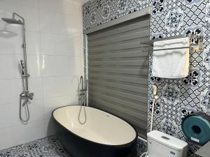 La salle de bains est pourvue d'une baignoire noire et de toilettes. dans l'établissement Azalea Tam Coc Ninh Bình, à Ninh Binh