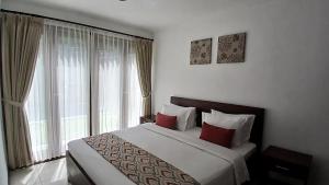 Schlafzimmer mit einem Bett mit roten Kissen und einem Fenster in der Unterkunft Sekuta Condo Suites in Sanur