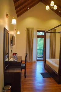 a bedroom with a bed and a desk and a table at Lion Gate Hotel Sigiriya in Sigiriya